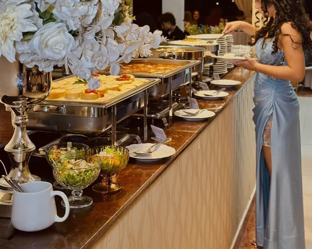 Balcão de buffet de jantar com rechauds de aço e arranjos de flores brancas