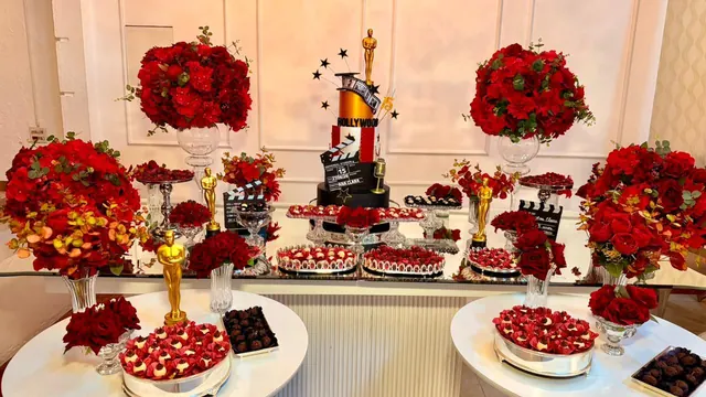 Mesa de doces vermelha com flores, bolo e taças de doces finos