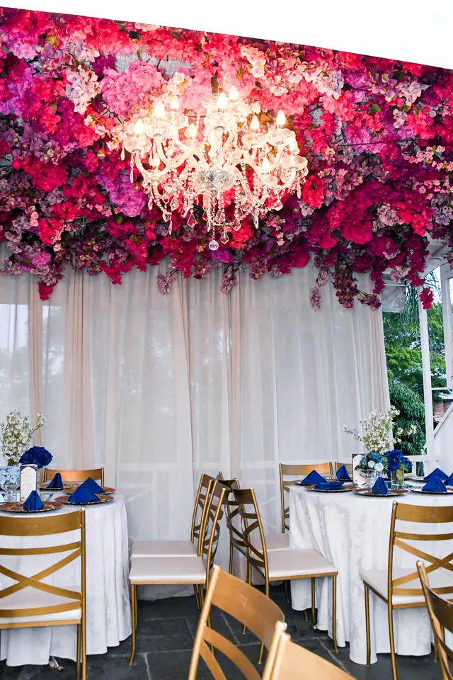 Varanda com teto de flores, cortinas brancas e mesas postas em azul e branco